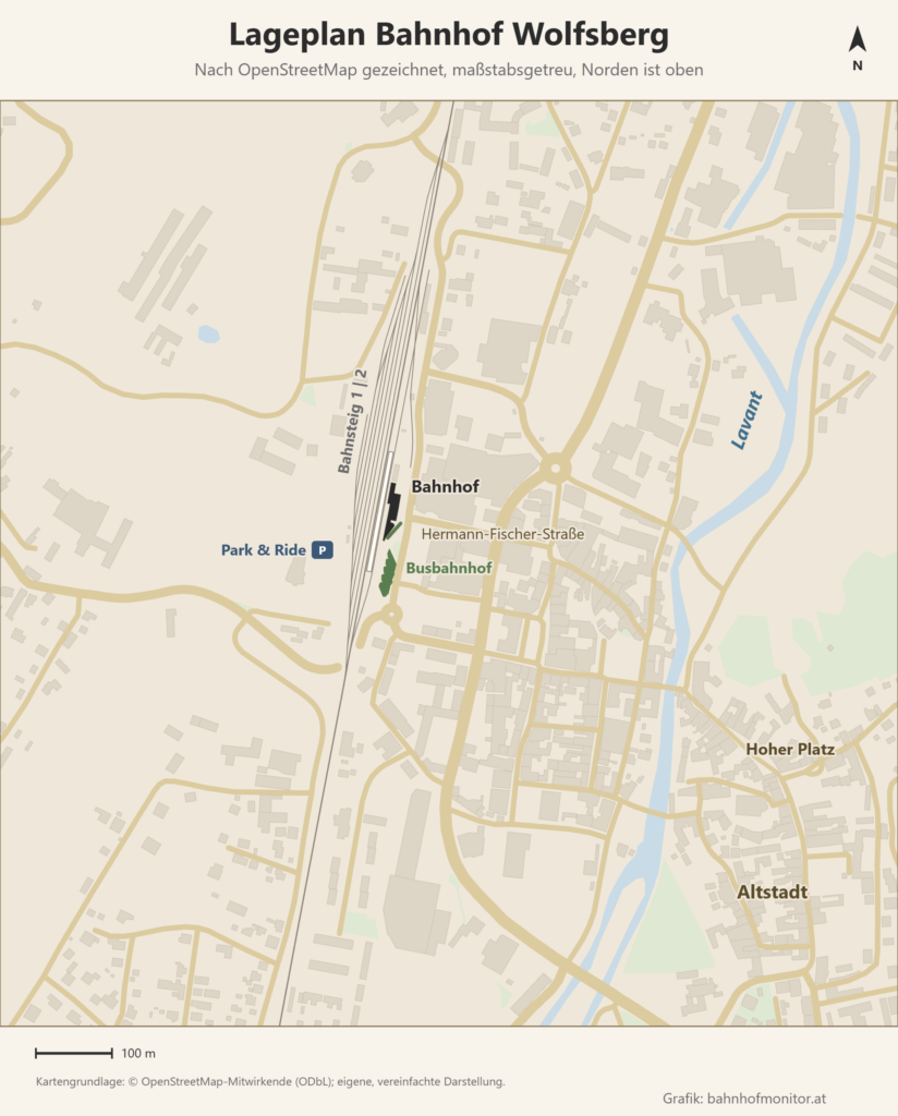 Maßstabsgetreuer Lageplan des Bahnhofs Wolfsberg nach OpenStreetMap, Norden oben: der von Norden nach Süden verlaufende Mittelbahnsteig mit den Gleisen 1 und 2, östlich das Bahnhofsgebäude und südlich davon der Busbahnhof, westlich der Gleise der Park-and-Ride-Parkplatz; im Osten die Lavant und die Altstadt mit dem Hohen Platz.